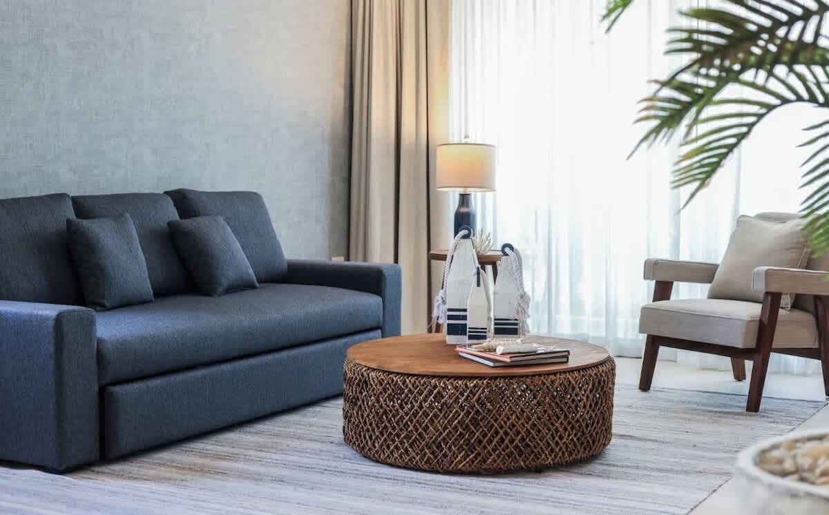 Een moderne woonkamer met een bank, een rond bijzettafeltje en een lamp.