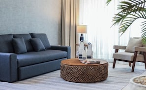 Een moderne woonkamer met een bank, een rond bijzettafeltje en een lamp.