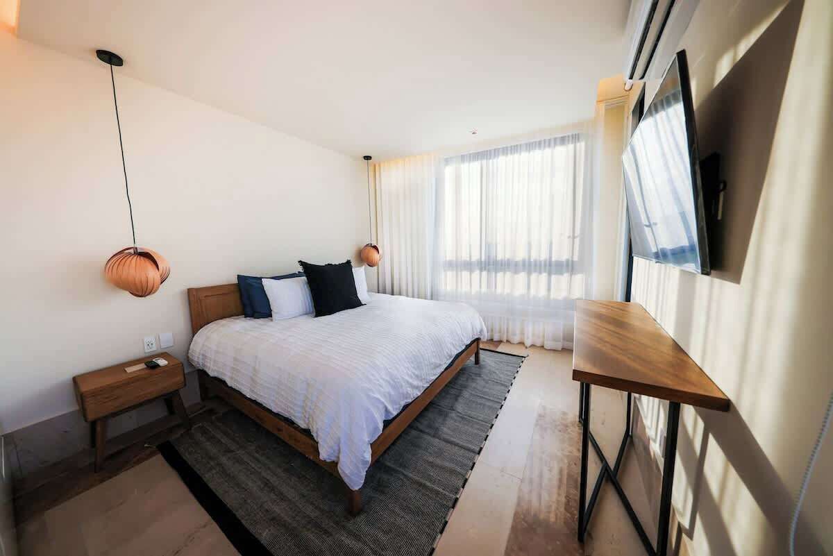 Ein modernes Hotelzimmer mit einem großen Bett, Nachttischen, einem Schreibtisch und einem Fernseher.