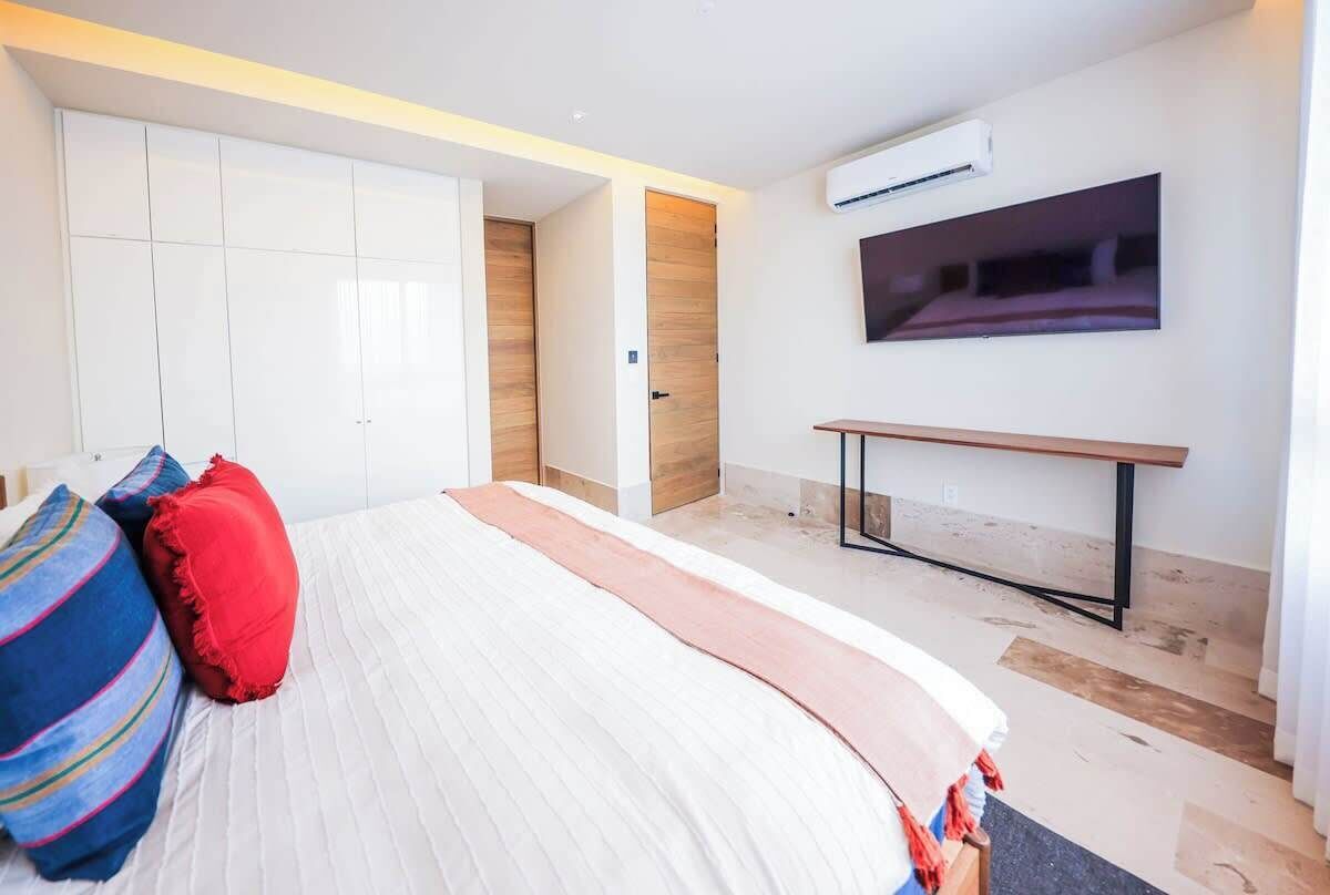 A bedroom with a bed, pillows, a bedside table, a TV, and a wardrobe.