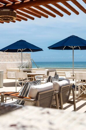 A beachside lounge with two umbrellas, lounge chairs, and a view of the ocean. - Apt Colibri: Coastal style with private terrace (Puerto Morelos)