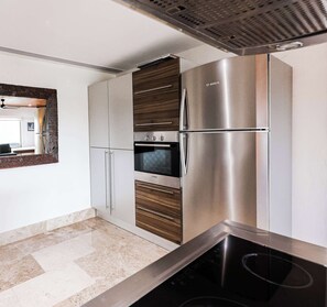 A modern kitchen with a Bosch refrigerator, oven, and a built-in stovetop. - La Amada | Rooftop Condo w Marina & Mangrove Views (Cancún)