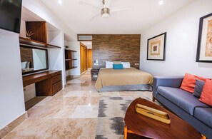 A modern bedroom with a bed, a sofa, a TV, and a ceiling fan.