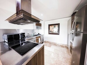 A modern kitchen with a built-in stove, stainless steel appliances, and a large refrigerator.