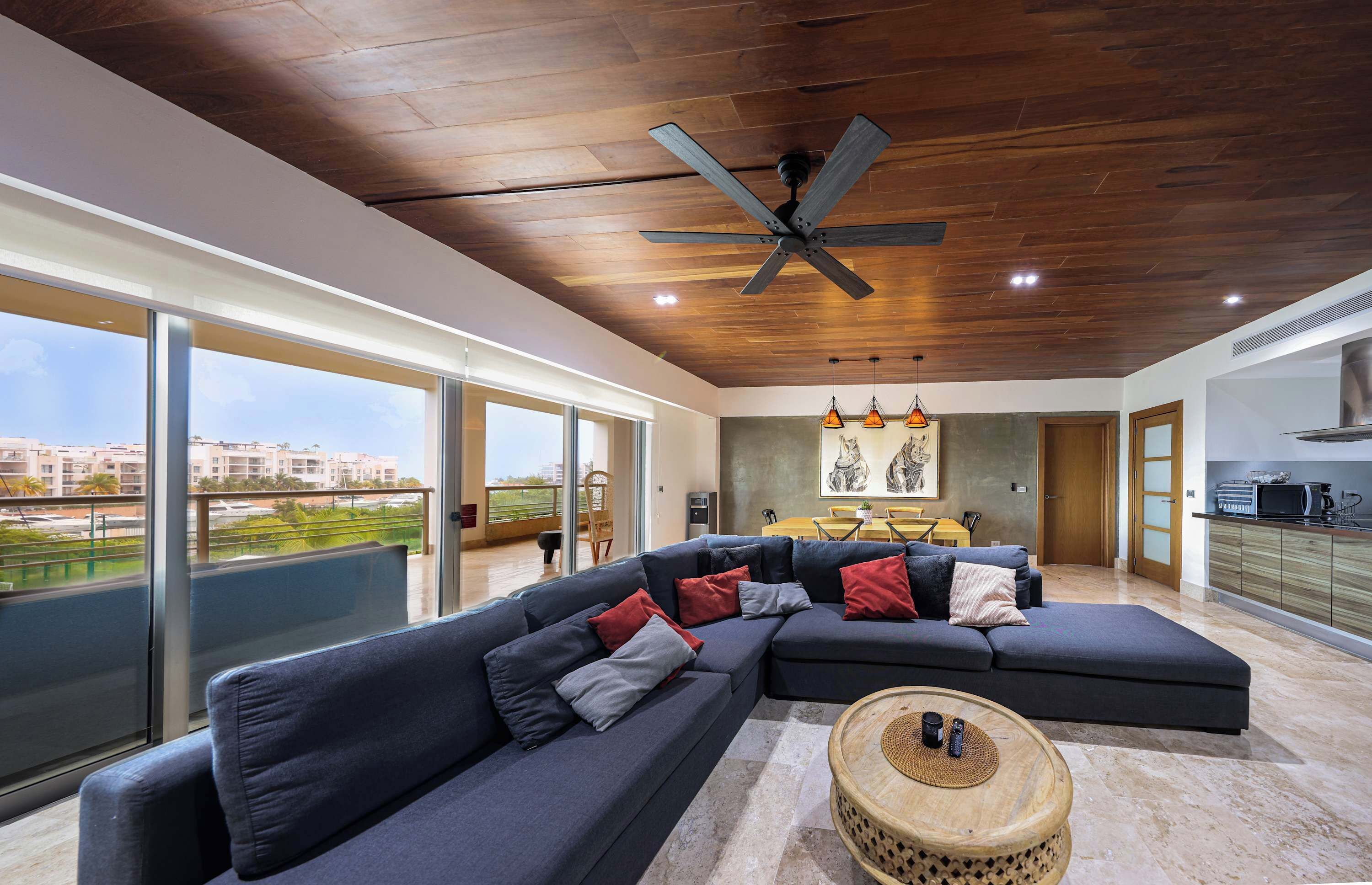 Uma sala de estar moderna com um sofá seccional, uma mesa de centro redonda e um ventilador de teto.