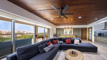 Uma sala de estar moderna com um sofá seccional, uma mesa de centro redonda e um ventilador de teto.