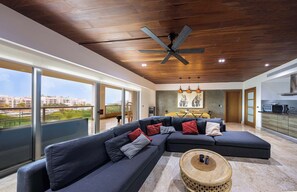 A modern living room with a sectional sofa, a round coffee table, and a ceiling fan.