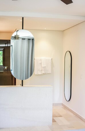 Un baño moderno con un espejo grande, un espejo redondo y una encimera blanca.