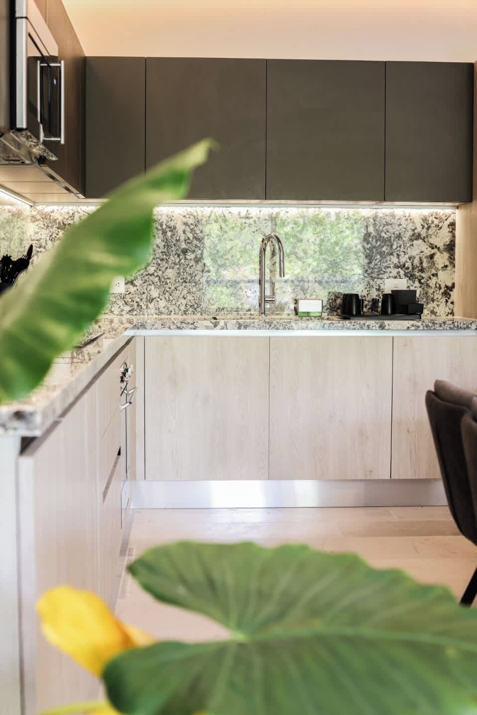 A modern kitchen with a granite countertop, stainless steel faucet, and wooden cabinets.