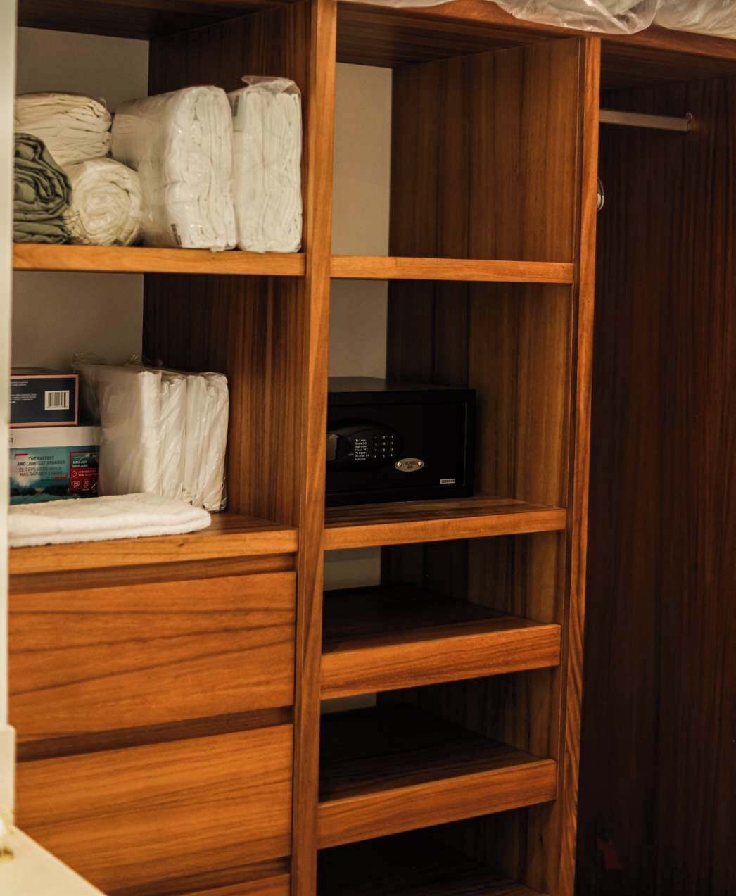 Ein Holzschrank mit mehreren Einlegeböden, auf einigen liegen gefaltete Handtücher und eine Packung Taschentücher.