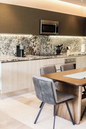 A modern kitchen with dark cabinets, a built-in microwave, a coffee maker, and a marble backsplash. - Apt Jaguarundi: Stylish Retreat with Shared Pool (Puerto Morelos)