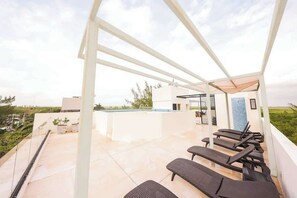 A rooftop terrace with lounge chairs, a pool, and a glass-enclosed area. - Gaia: Retreat Close to the Sea in Puerto Morelos (Puerto Morelos)