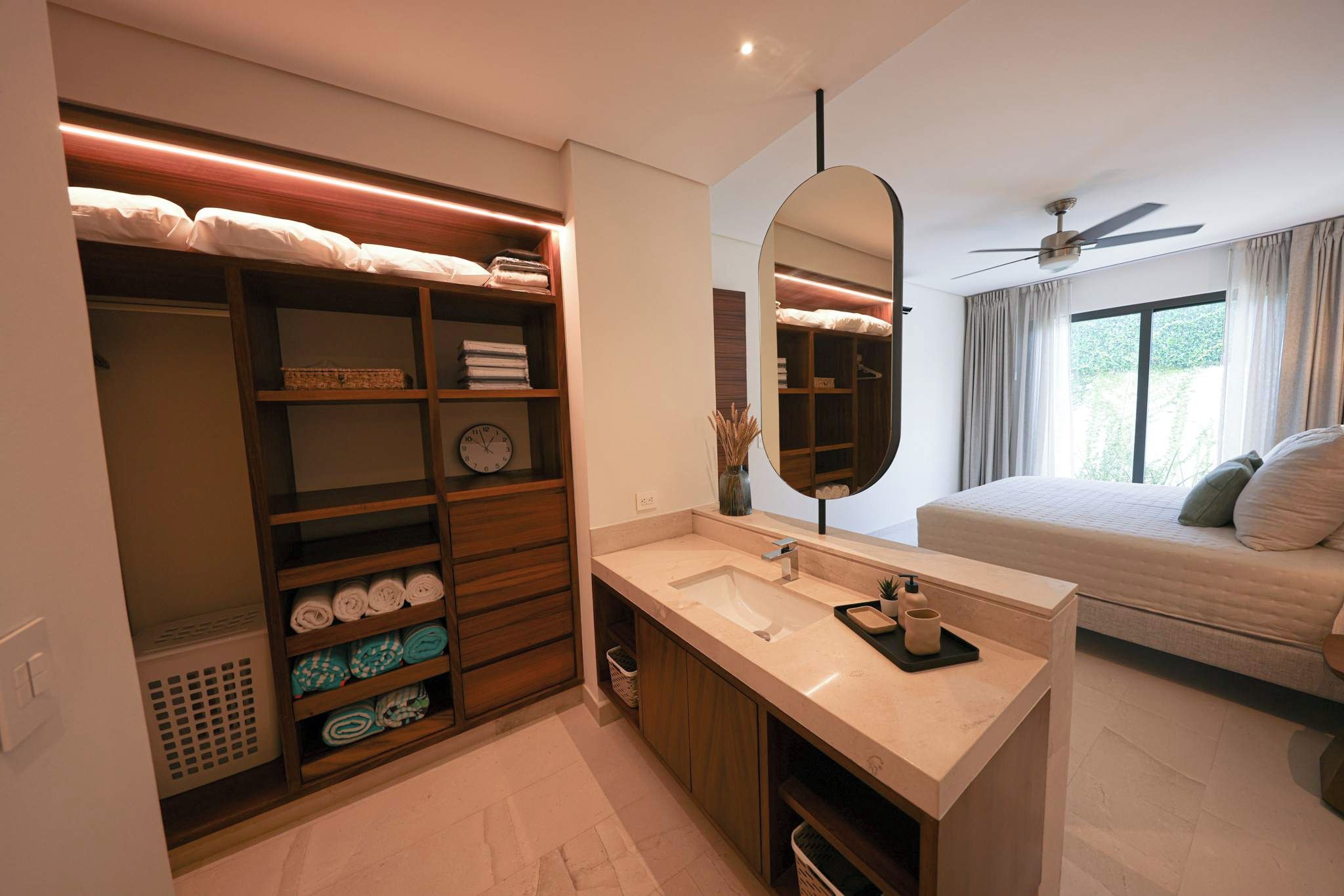 A modern bathroom with a built-in vanity, a large mirror, and a ceiling fan.