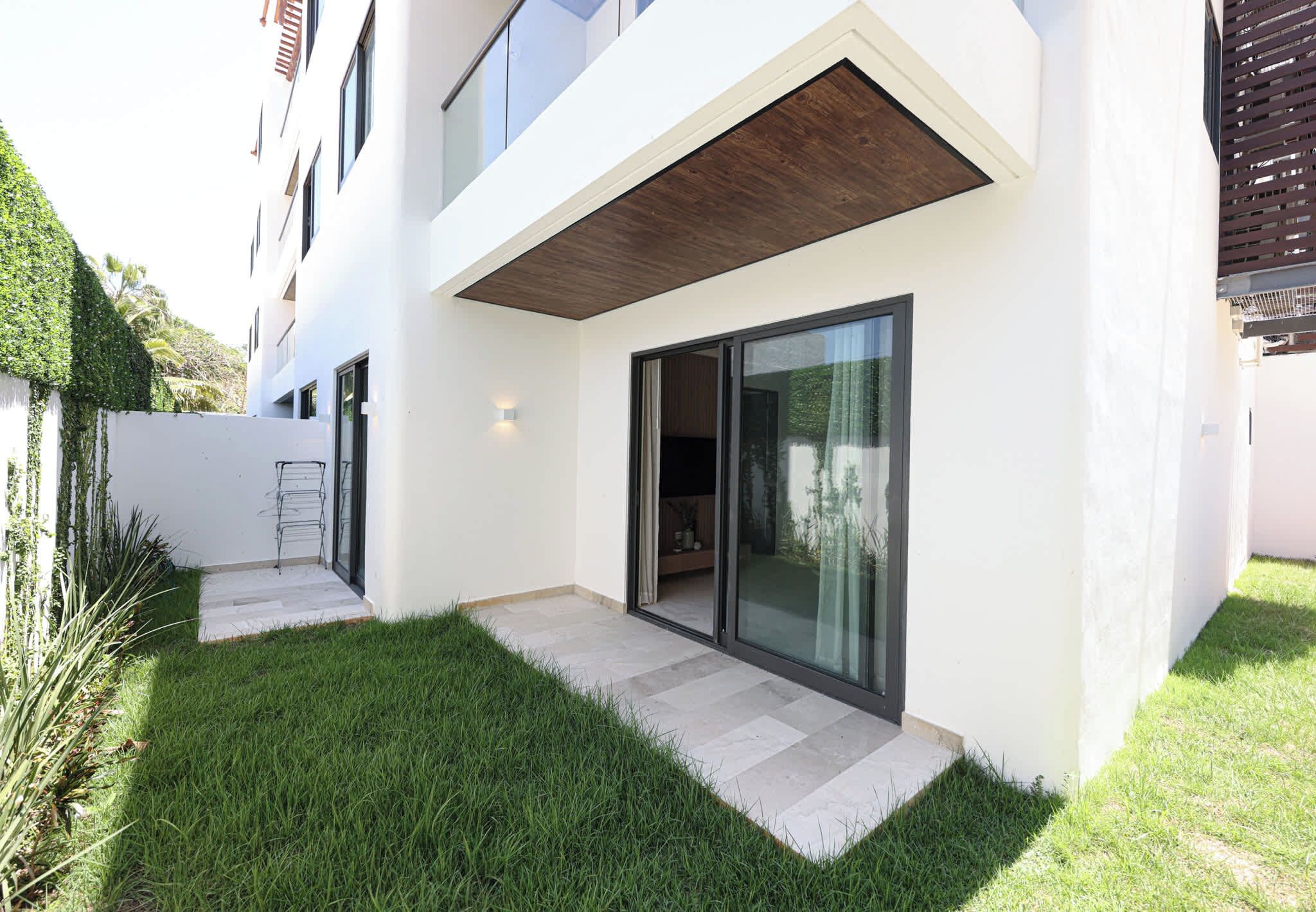 Een modern gebouw met twee verdiepingen, een plat dak, grote schuifdeuren en een klein terras.