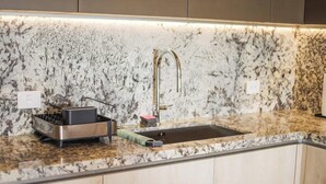 A kitchen with a granite countertop, stainless steel appliances, and a modern faucet. - PH Tucán: Private Terrace and Ocean View rooftop (Puerto Morelos)