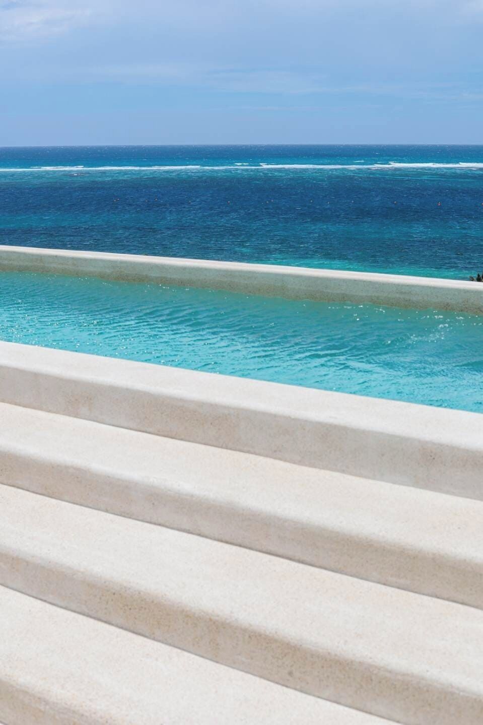 Una piscina con agua cristalina y vistas al océano.
