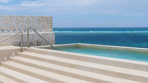 A pool with steps leading to the water, a clear view of the ocean, and a patterned fence in the background. - PH Tucán: Private Terrace and Ocean View rooftop (Puerto Morelos)