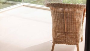 A wicker chair on a balcony with a glass railing, overlooking a green landscape. - PH Tucán: Private Terrace and Ocean View rooftop (Puerto Morelos)