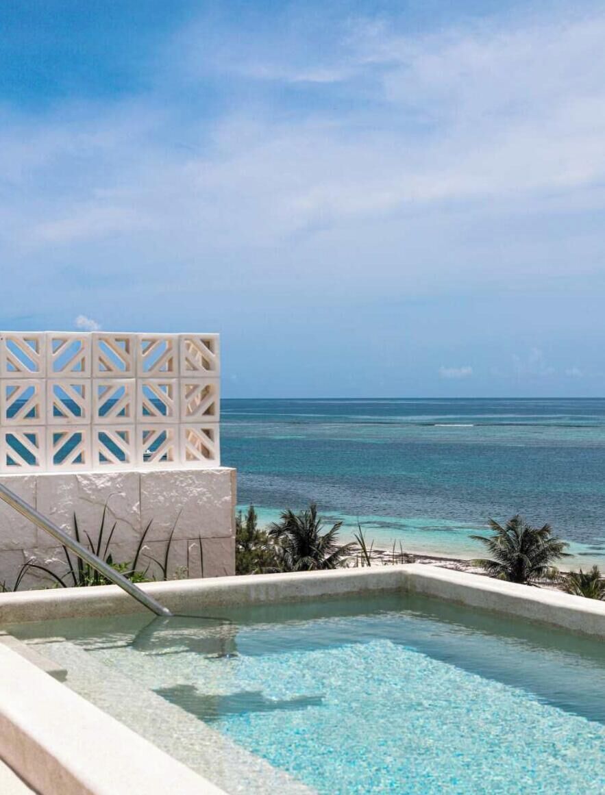 Ein Pool mit freiem Blick auf den Ozean und einer weißen Struktur mit Gittermuster.