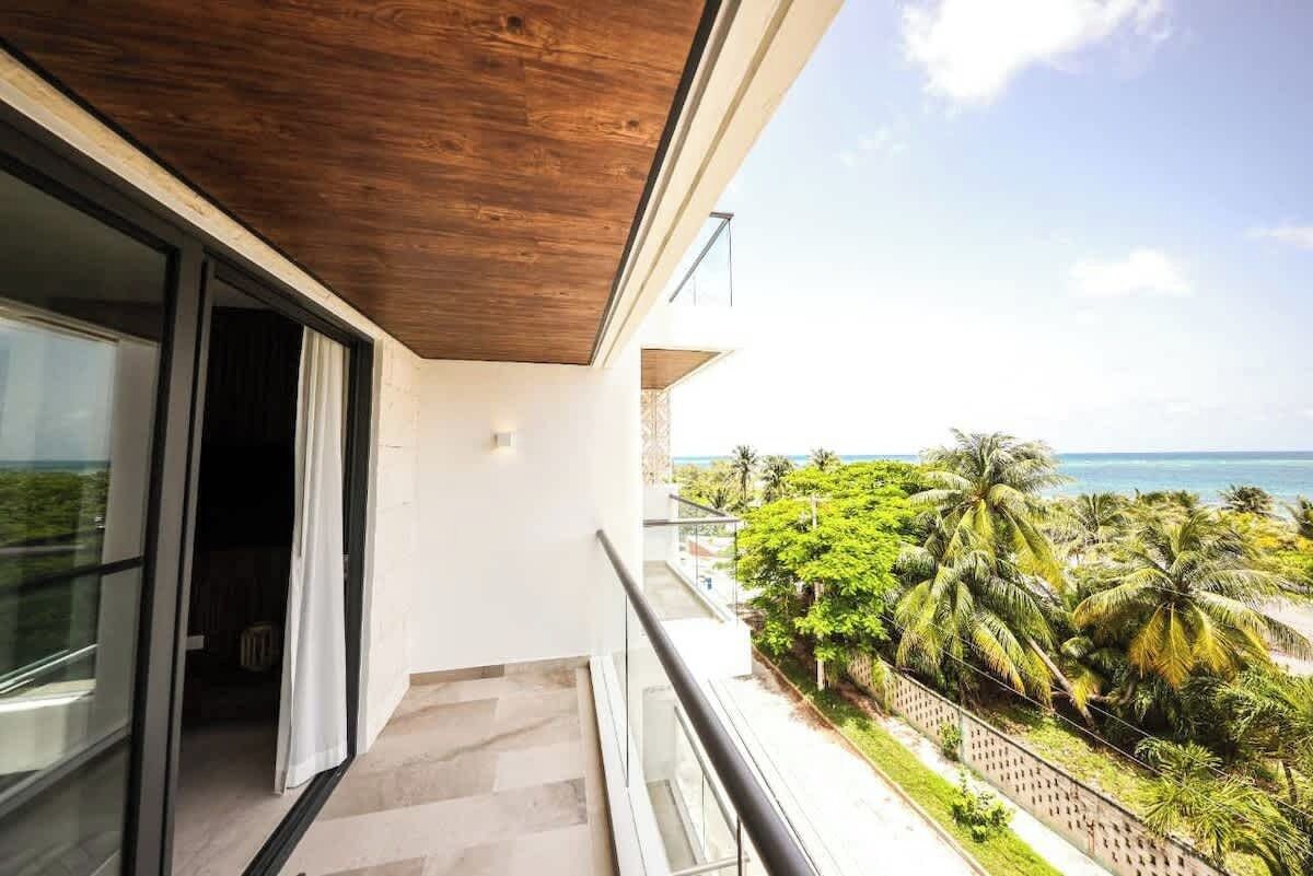 A balcony with a view of palm trees and the ocean.