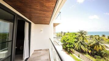 A balcony with a view of palm trees and the ocean.