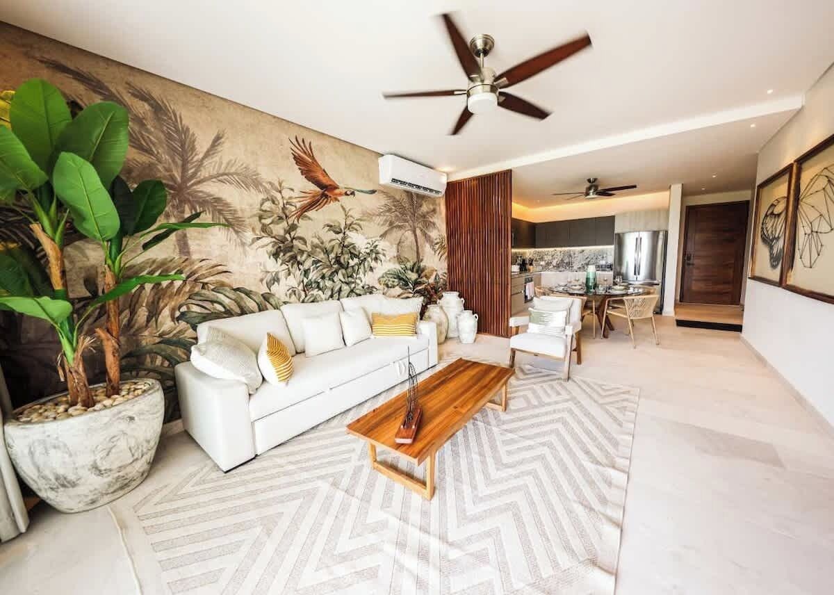 A modern living room with a white sofa, a wooden coffee table, and a large potted plant.