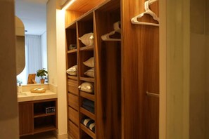 Ein Holzkoffer mit zahlreichen Regalen und Kleiderstange, ein Spiegel und ein Blumentopf.