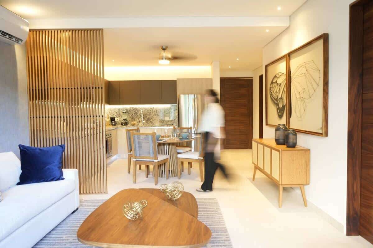 A modern living room with a sofa, a coffee table, and a dining area with chairs and a table.