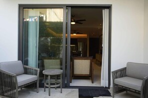 Ein Balkon mit zwei grauen Sofas, einem kleinen runden Tisch und einem Korbstuhl.