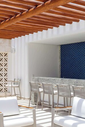 An outdoor seating area with white chairs and a wooden pergola overhead. - Apt Quetzal: Coastal retreat, Shared Rooftop & Poo (Puerto Morelos)