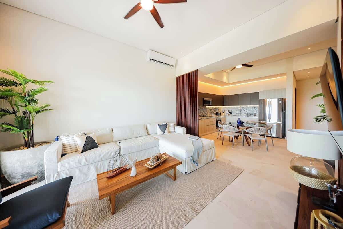 A modern living room with a sofa, coffee table, and a dining area with chairs.