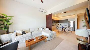 A modern living room with a sofa, coffee table, and a dining area with chairs.