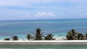 A beach with clear turquoise water and palm trees. - Apt Jaguar: Balcony with Sea View & Rooftop Pool (Puerto Morelos)
