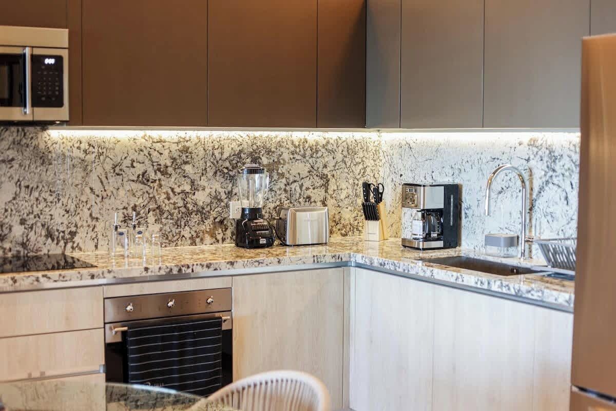 A modern kitchen with a granite countertop, a built-in oven, a coffee maker, and a microwave.