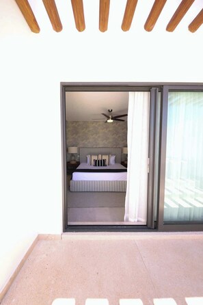 A bedroom with a bed, pillows, a ceiling fan, and a view through a sliding door. - Apt Mantarraya: Private Plunge Pool & Terrace (Puerto Morelos)