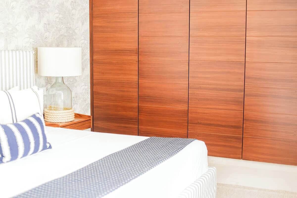 Une chambre à coucher avec un lit, une table de chevet avec une lampe et une armoire en bois.