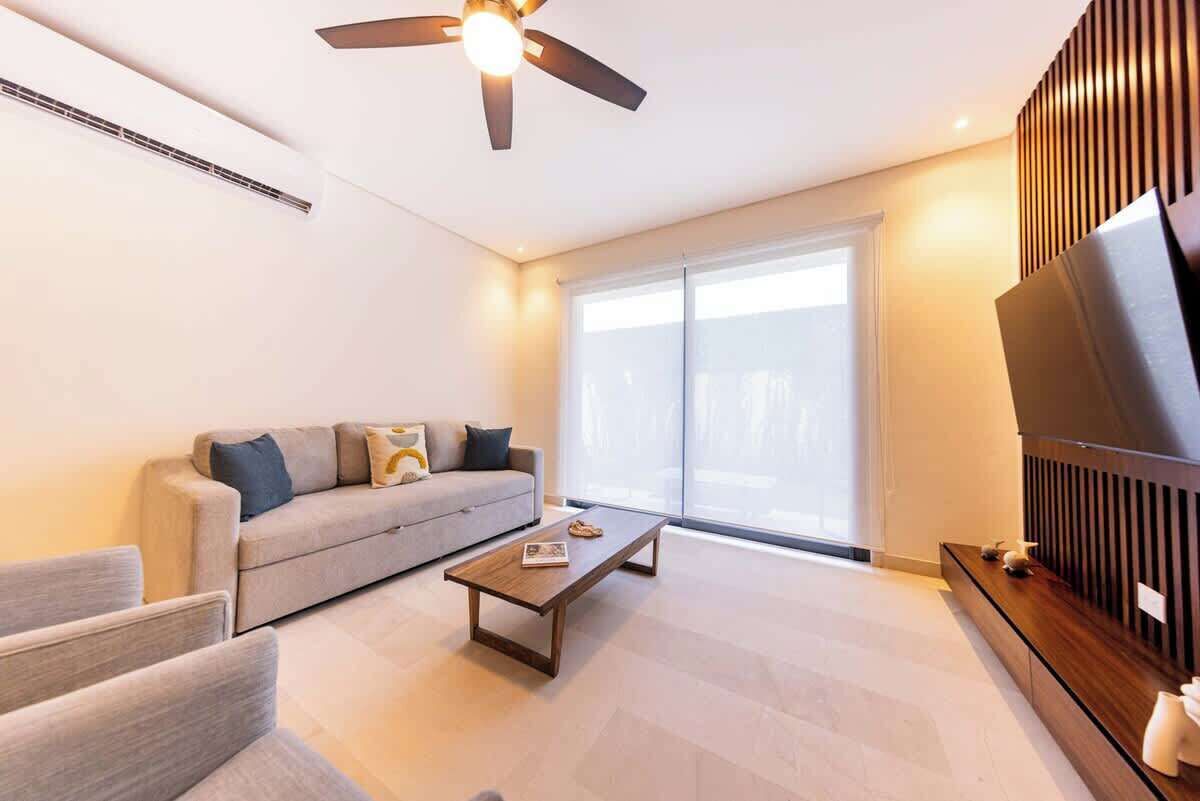 A modern living room with a sofa, a coffee table, and a ceiling fan.
