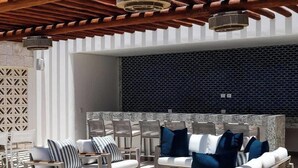 An outdoor seating area with a modern design, featuring a patterned wall and a wooden pergola overhead.