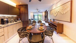 A modern kitchen with a dining area, featuring a round table with chairs, a ceiling fan, and a large abstract painting on the wall.