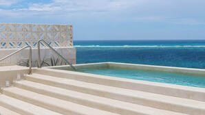 A pool with steps leading to the water, surrounded by a white fence with a geometric pattern.