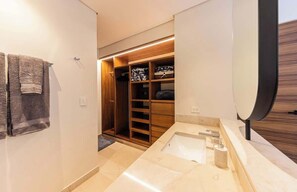 Een moderne badkamer met een grote spiegel, een wastafel en een inloopkast met houten planken.