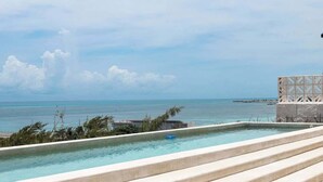Ein Pool mit Infinity-Kante auf dem Dach, mit Blick auf das Meer und einen entfernten Steg.