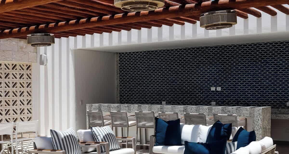 Un espacio de estar al aire libre con diseño moderno, que presenta una pared con estampado y una estructura de techo de madera.