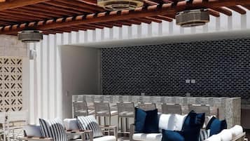 Un espacio de estar al aire libre con diseño moderno, que presenta una pared con estampado y una estructura de techo de madera.