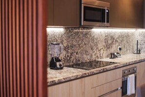 A modern kitchen with a granite countertop, a built-in microwave, and a blender. - Apt Flamingo: Relaxing Getaway with Shared Pool (Puerto Morelos)