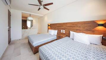 Habitación de hotel con dos camas, ventilador de techo y cabecera de madera.