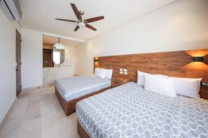 Ein Hotelzimmer mit zwei Betten, einem Deckenventilator und einem hölzernen Kopfteil.