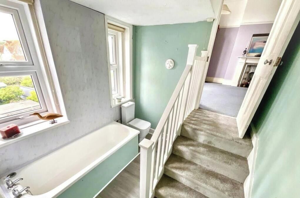 A bathroom with a bathtub, a window, and a toilet.