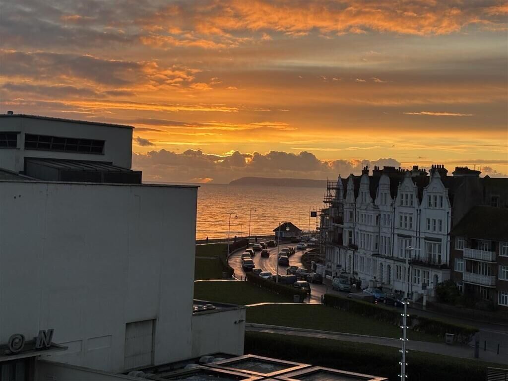A coastal sunset view with buildings and a road.