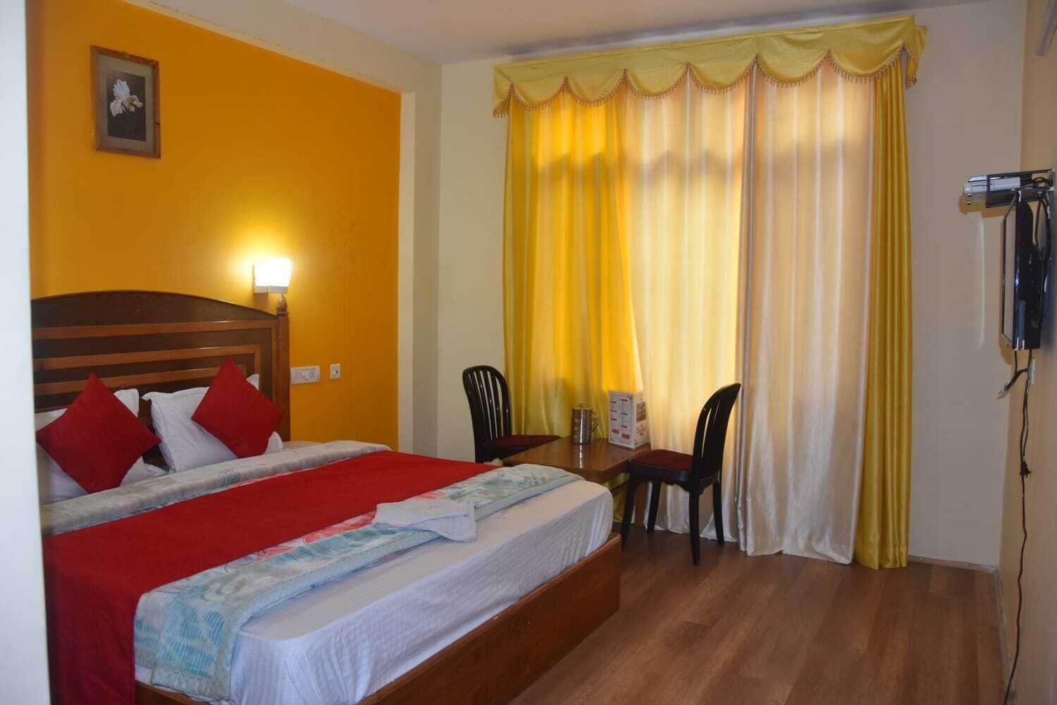 Una habitación de hotel con cama, escritorio, sillas, teléfono y un cuadro en la pared.